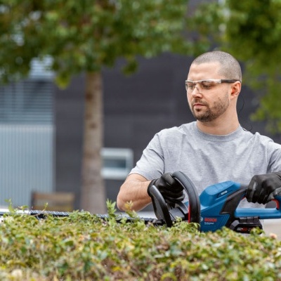 Homem a usar tesoura elétrica para podar sebes
