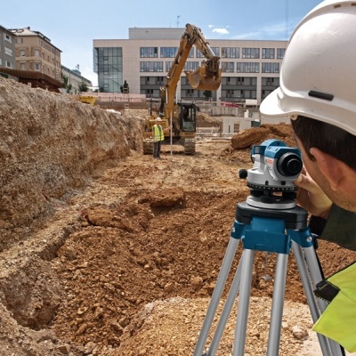 Equipamento topográfico e trabalhadores numa obra com terra marrom