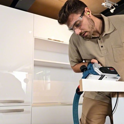 Homem a trabalhar com máquina de carpintaria em cozinha moderna