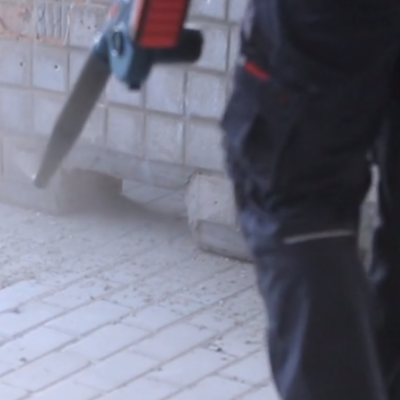 Serra de fita portátil a cortar blocos brancos em obra com parede cinza ao fundo