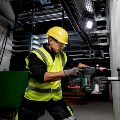 Homem a usar broca elétrica para perfurar parede de cimento