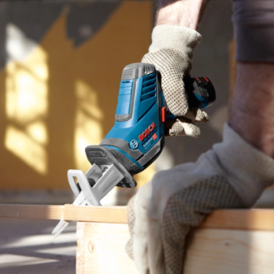Ferramenta de serra recíproca BOSCH azul a cortar madeira clara com pessoa usando luvas cinzentas.
