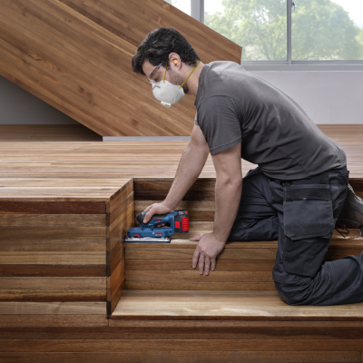 Homem a cortar degraus de madeira com serra elétrica