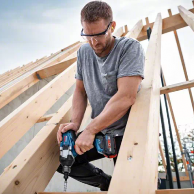 Homem a usar parafusadeira numa estrutura de madeira ao ar livre