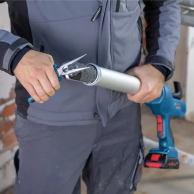 Homem a segurar pistolas de calafetagem manual e elétrica