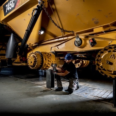 Caminhão articulado amarelo em oficina com trabalhador a reparar