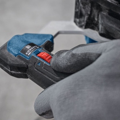 Ferramenta de aperto preta e azul com detalhe vermelho na mão com luva cinzenta