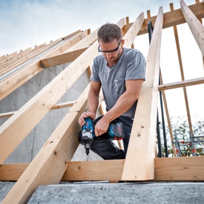 Homem a usar furadeira em estrutura de madeira para telhado