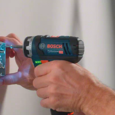 Parafusadeira elétrica BOSCH azul e preta usada em instalação elétrica na parede branca