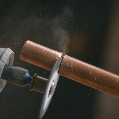 Ferramenta elétrica a cortar tubo de cobre com discos criando fagulhas