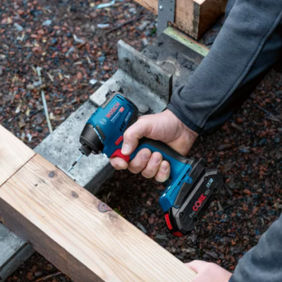 Parafusadeira elétrica a carregar parafuso em madeira clara