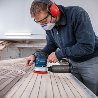 Homem a lixar superfície de madeira com lixadora BOSCH num atelier