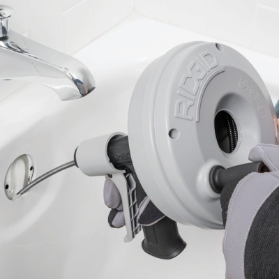 Máquina desentupidora de canos Rigid usada num lavatório branco tipicamente doméstico