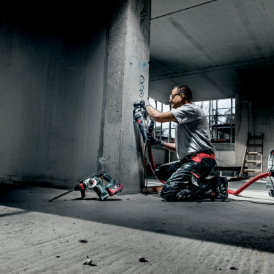 Homem a usar ferramenta elétrica para polir coluna de betão num interior em construção
