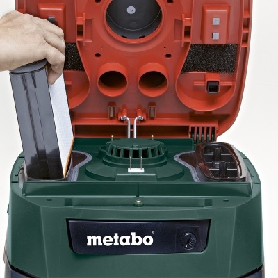 Aspirador de pó Metabo verde e vermelho com mão inserindo filtro