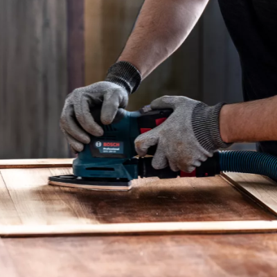 Pessoa a lixar porta de madeira com lixadora elétrica Bosch