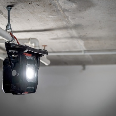 Projetor de luz preto suspenso no teto de cimento com lâmpada acesa