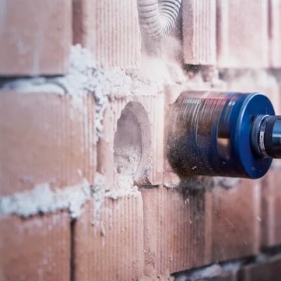 Ferramenta elétrica com broca azul perfurando parede de tijolos