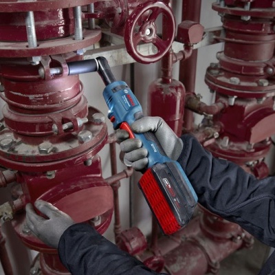 Pessoa a usar ferramenta elétrica numa tubagem vermelha