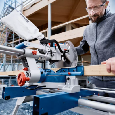 Serra de corte Bosch em bancada azul num canteiro de obras com operador a usar equipamento de proteção
