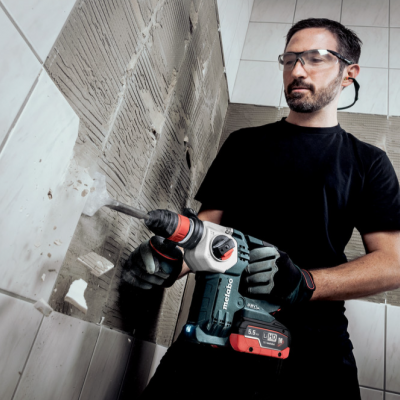 Homem a usar corta azulejos elétrico em parede de azulejos brancos