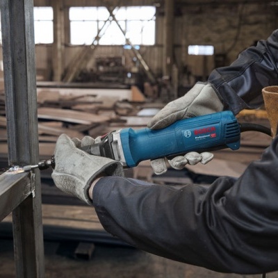 Pessoa a usar ferramenta elétrica azul para cortar metal numa oficina