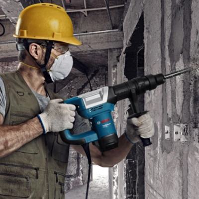 Trabalhador com ferramenta eléctrica Bosch a perfurar parede