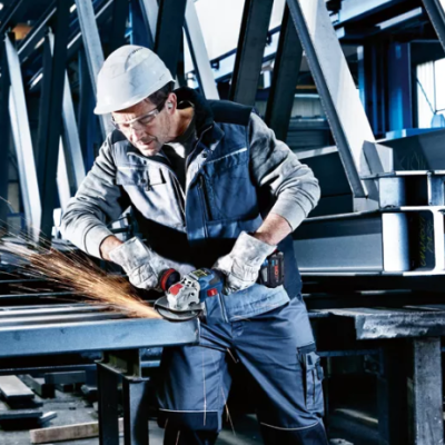 Homem a cortar metal com esmerilhadora numa estrutura metálica industrial