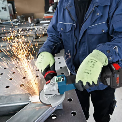 Trabalhador com rebarbadora a cortar barra metálica numa mesa de metal