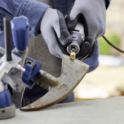 Pessoa a lixar lâmina metálica curva com ferramenta rotativa numa oficina