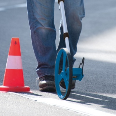 Medição de distância com roda de medição azul no asfalto entre cones de trânsito
