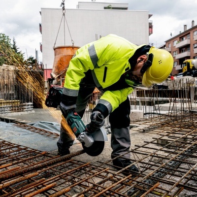 Trabalhador de construção com esmerilhadeira cortando vergalhões