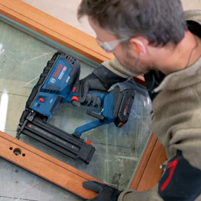 Homem a usar pistola de pregos BOSCH numa moldura de madeira