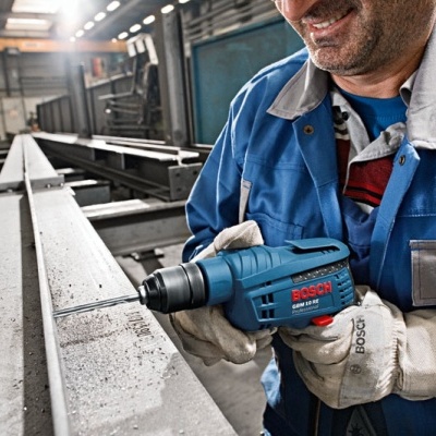 Broca elétrica Bosch azul usada por trabalhador com luvas num ambiente industrial