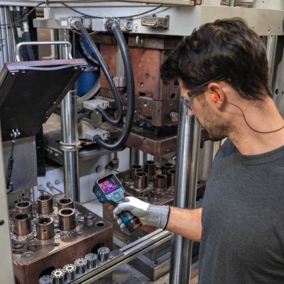 Homem usando dispositivo portátil para inspeção numa linha de montagem industrial