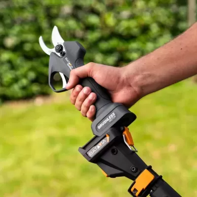 Tesoura elétrica de poda com motor brushless em ambiente de jardim.