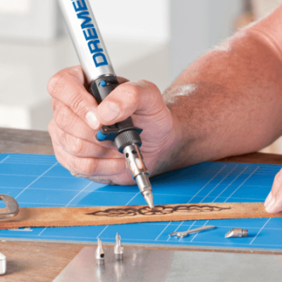 Pessoa usando ferramenta DREMEL para gravar em régua de madeira