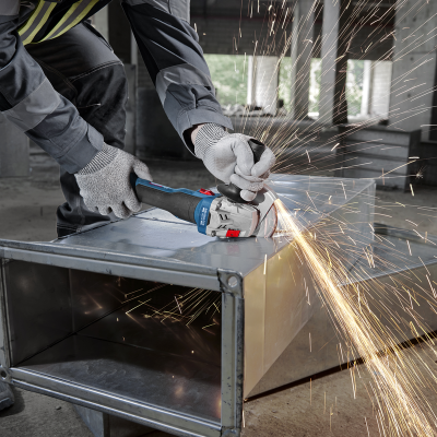 Pessoa a usar rebarbador para cortar caixa metálica com faíscas na construção