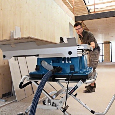 Serra de bancada azul e cinza com aspirador de pó em ambiente de construção