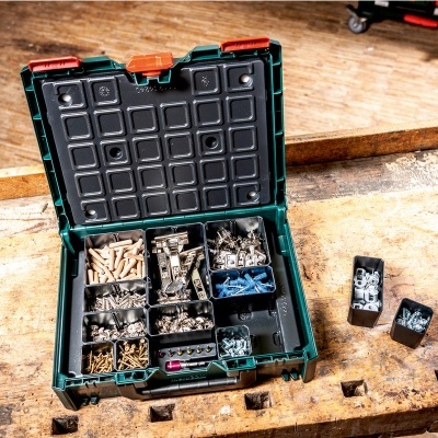 Caixa organizadora verde com parafusos e cavilhas sobre bancada de madeira