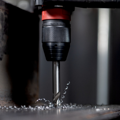 Broca metálica a perfurar chapa de metal numa furadeira elétrica