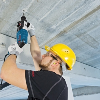 Homem a perfurar teto de cimento com ferramenta elétrica