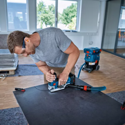Homem a cortar placa preta com serra elétrica num ambiente de trabalho