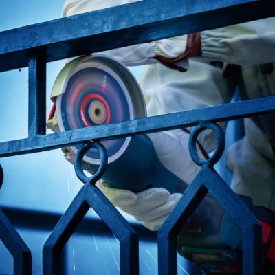 Trabalhador corta corrimão metálico azul com ferramenta elétrica