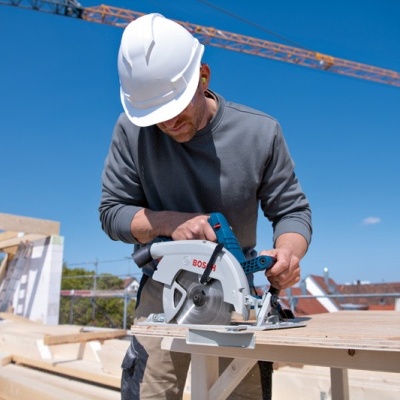 Serra circular BOSCH a ser usada por operário em obra ao ar livre