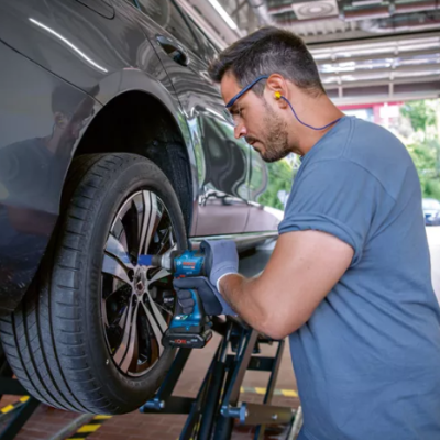 Homem a apertar parafusos da roda de um carro numa oficina