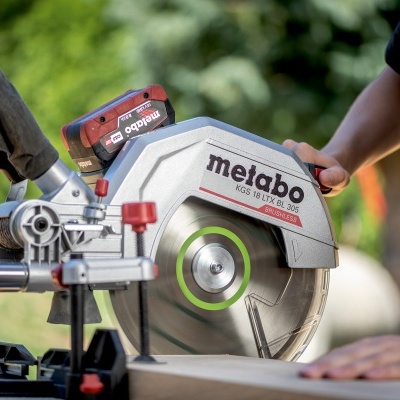 Serra de disco Metabo cinzenta e vermelha com saco de pó preto operada ao ar livre