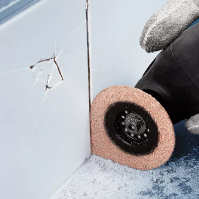 Disco abrasivo sendo usado numa ferramenta elétrica em superfície branca