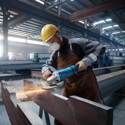 Trabalhador a cortar metal com esmeriladora num ambiente industrial