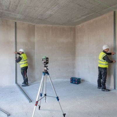 Operários a instalar perfis metálicos em paredes de divisão em construção.